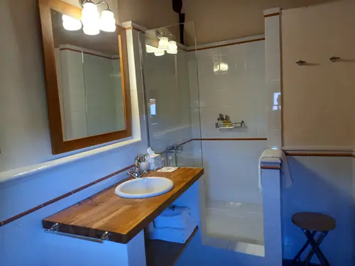 Baño privado con acabados cuidados y ducha amplia en habitación de hotel rural