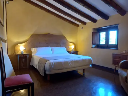 Habitación doble amplia con cama de matrimonio y decoración cálida en hotel rural con encanto